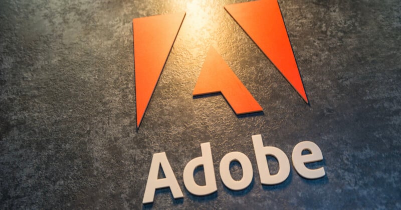 The image shows the Adobe logo, featuring a stylized red "A" on a textured dark surface, with the name "Adobe" written in white capital letters below the logo.