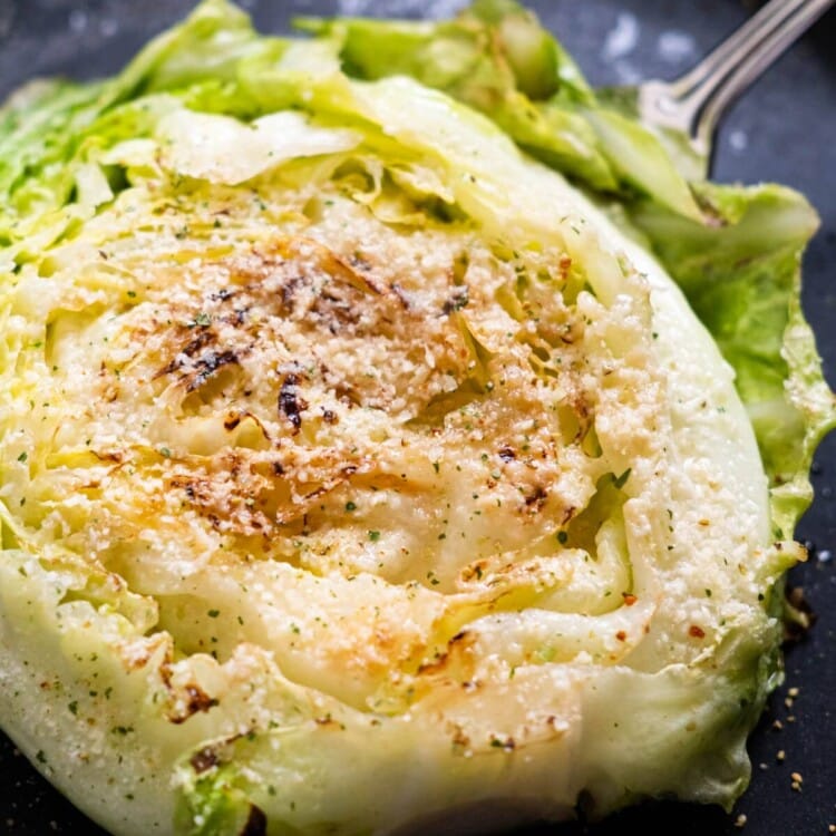 Cabbage steaks in a pan served with grated parmesan cheese.