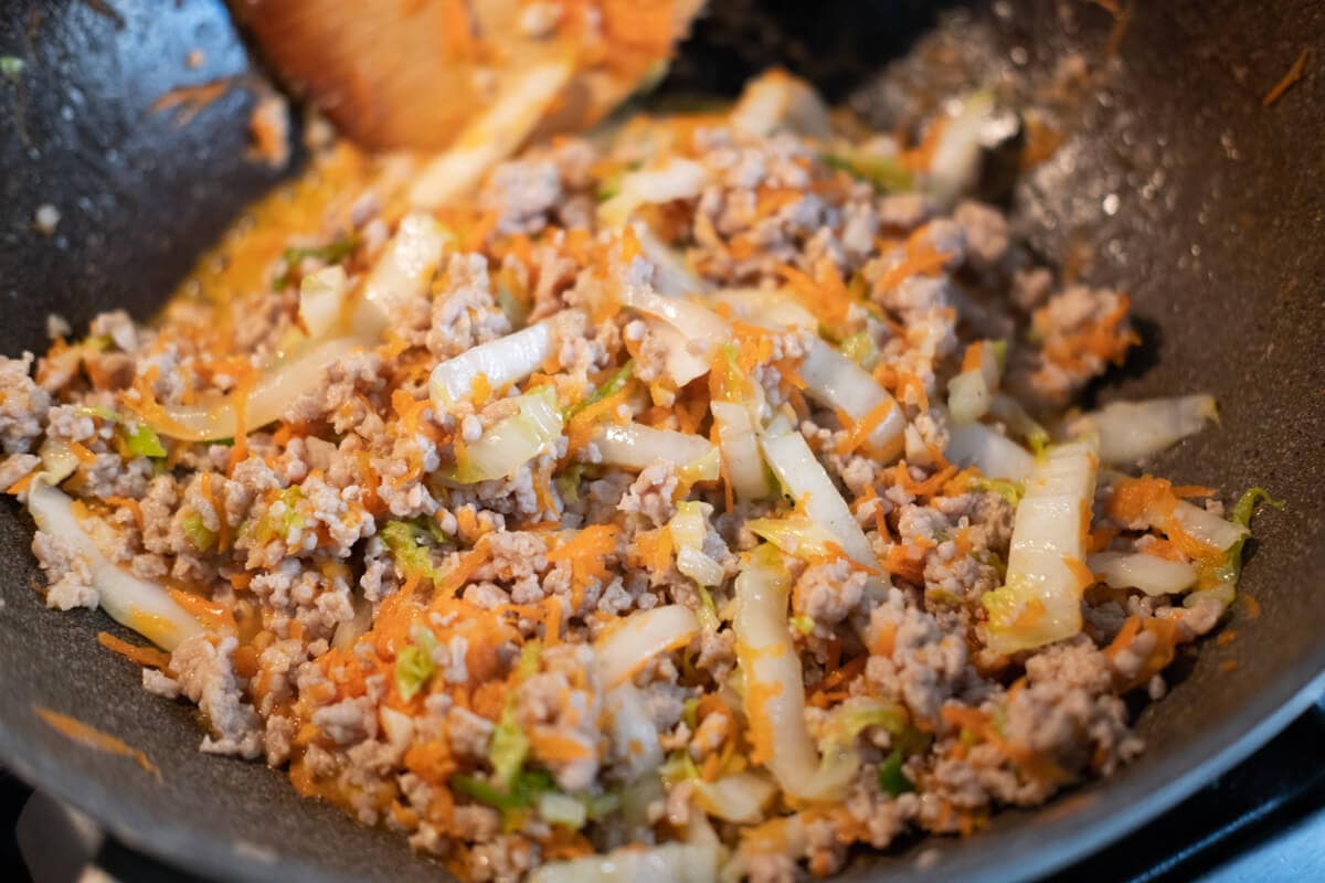 Stir-fry ground chicken with other vegetables in a wok. 