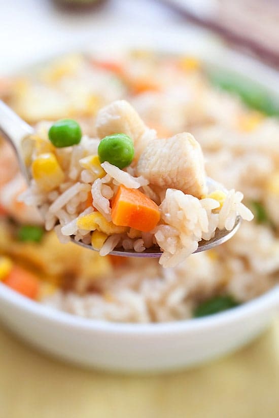 Chinese takeout egg fried rice with chicken, shrimp and vegetable on a spoon.