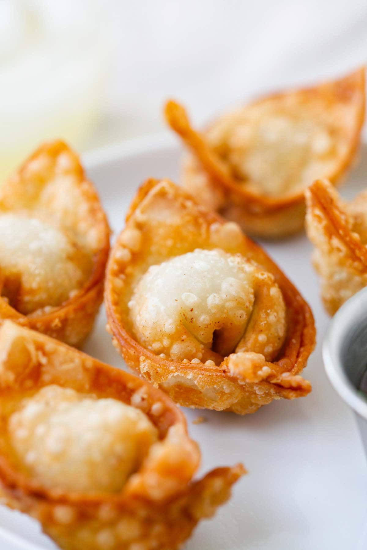 A plate of fried wontons ready to serve with sweet and sour sauce.
