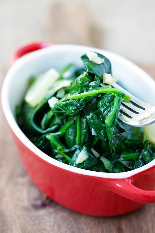 Healthy homemade sauteed baby spinach with garlic butter picked with a fork, ready to serve.