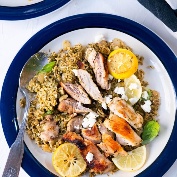 One-pan Greek chicken and rice is served with seared lemon slices and Feta cheese crumbles.