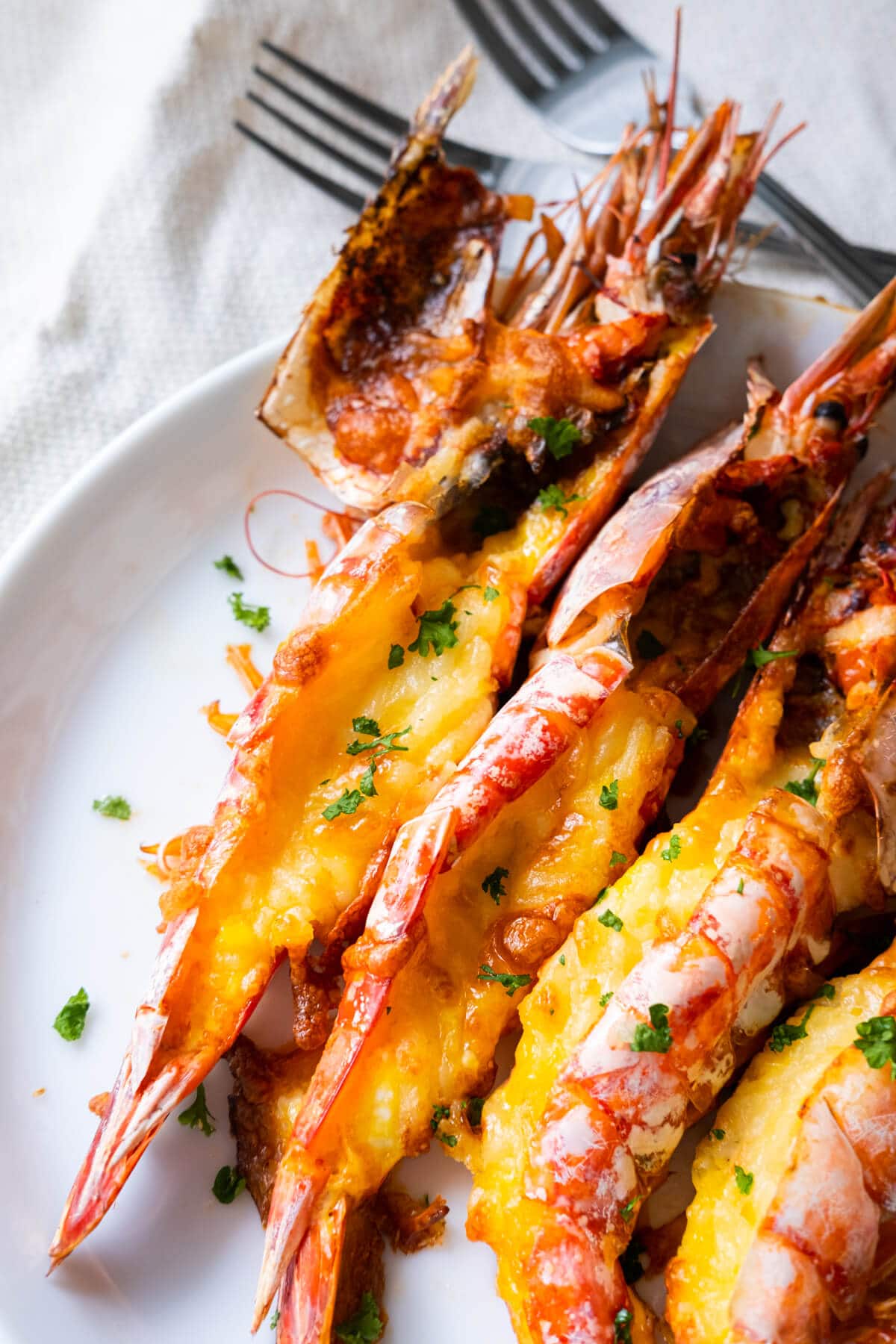 Grilled cheese prawns on a white shallow plate. 