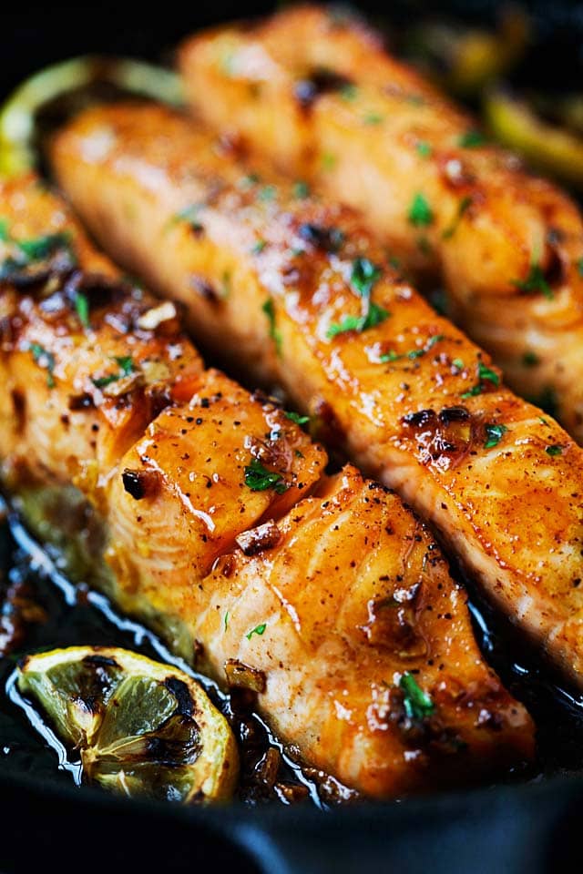 Salmon fillet with honey garlic sauce cooked on stove.