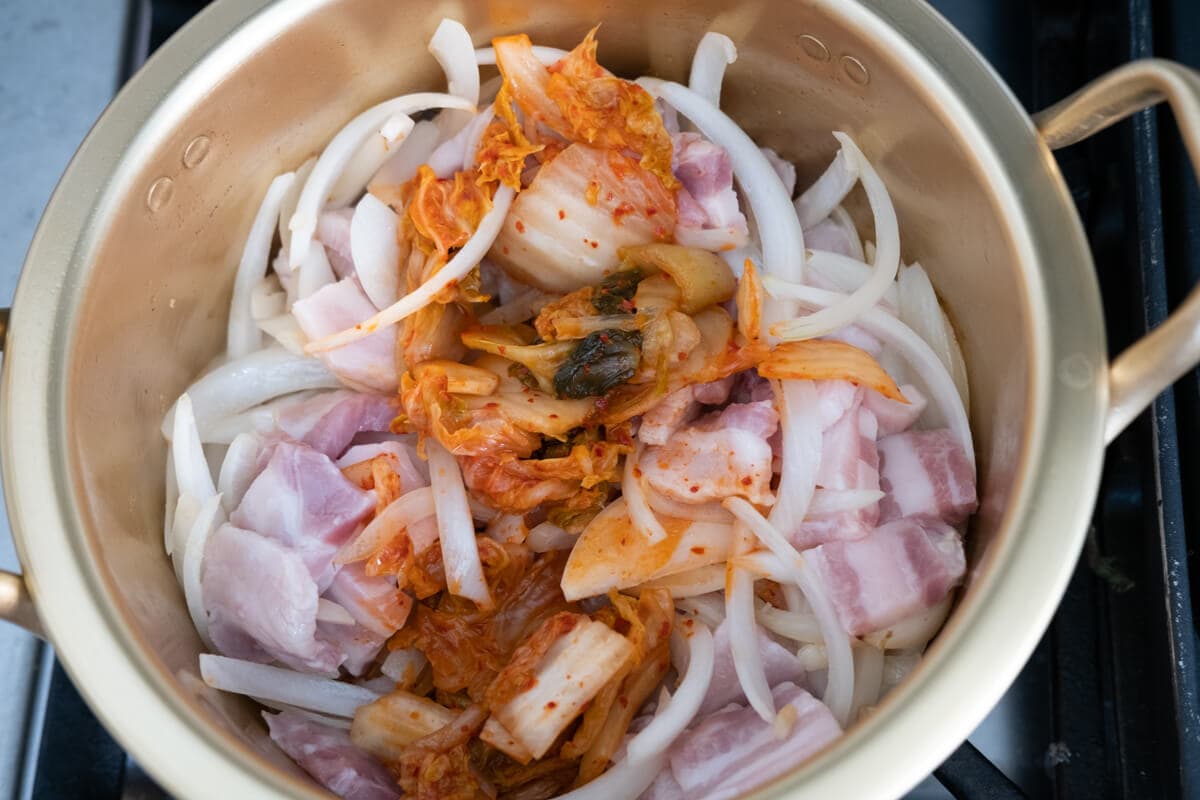 Stir-fry onion, kimchi and pork belly in the pot. 