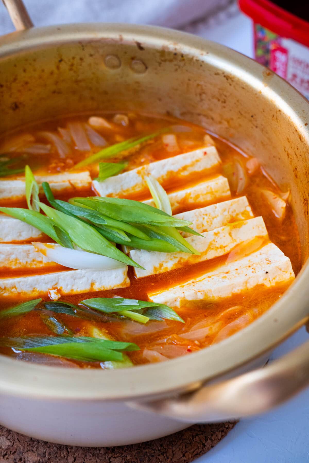 Easy kimchi jjigae in red kimchi stew with firm tofu, pork belly and onion slices.