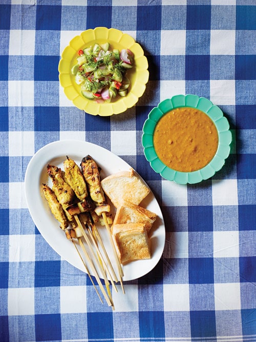 Easy homemade char grilled pork skewers, Thai Pork Satay, served in a plate with a side of Asian greens and satay peanut dipping sauce.