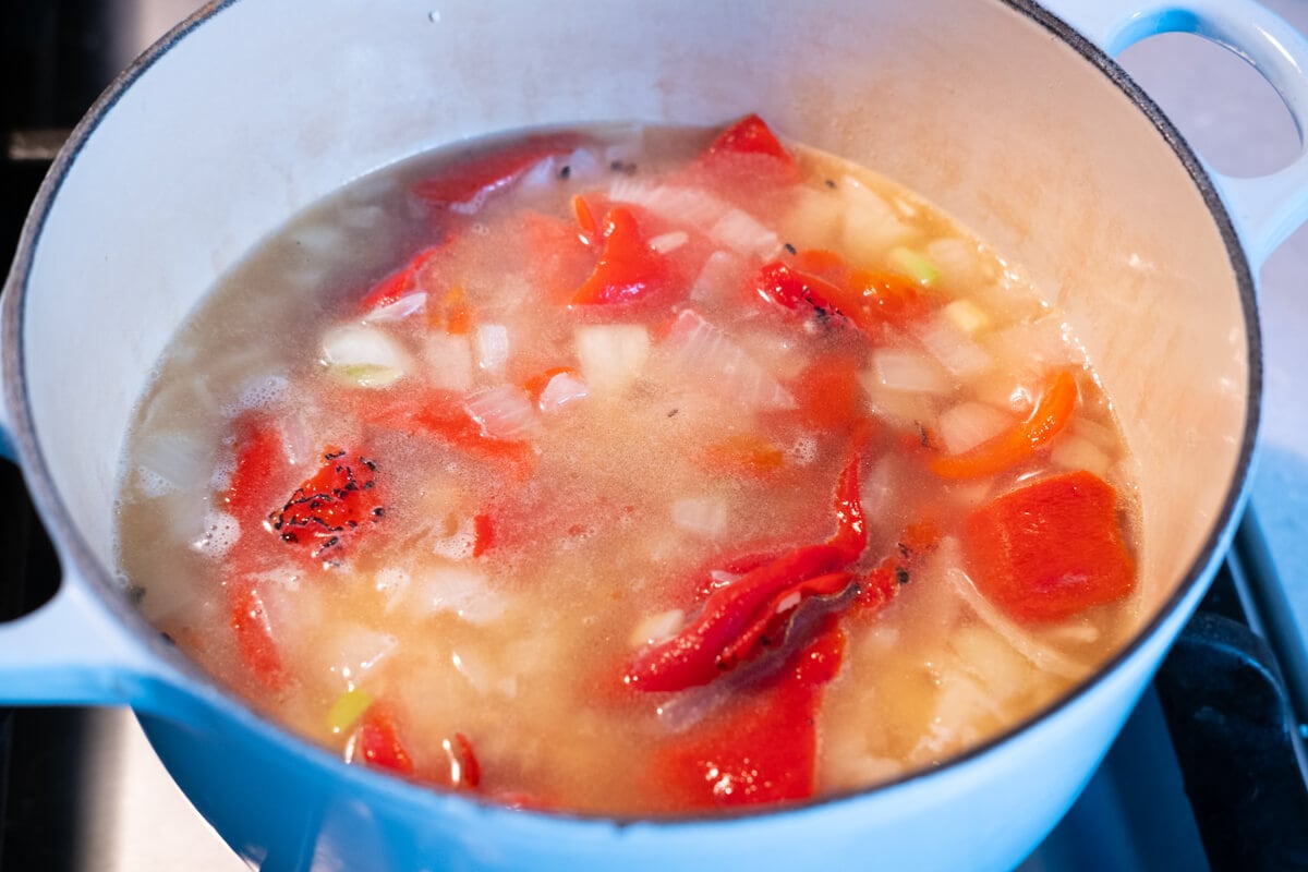 Boil the mixture of rice, onion, garlic, roasted red pepper and chicken stock in a pot. 