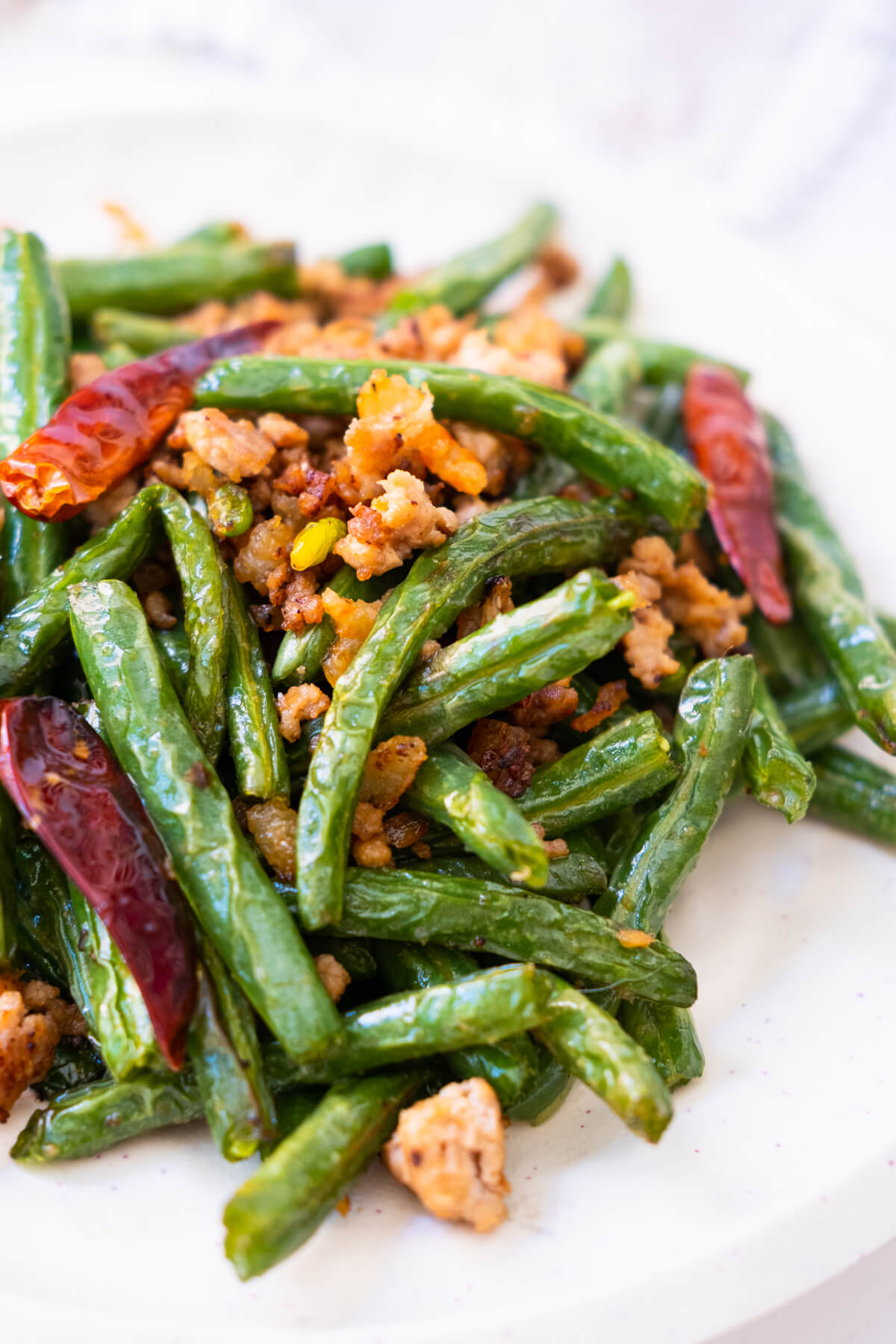 Deep-fried Sichuan green beans with dried shrimp, ground pork and dried chilies in a white platter.