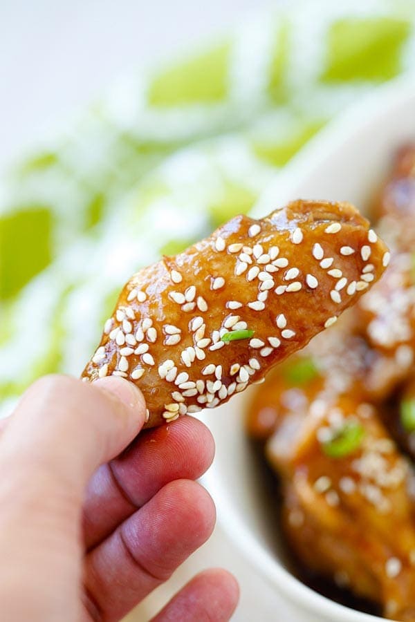 Honey Sesame Chicken Wings in a sticky savory honey sesame sauce picked with finger.