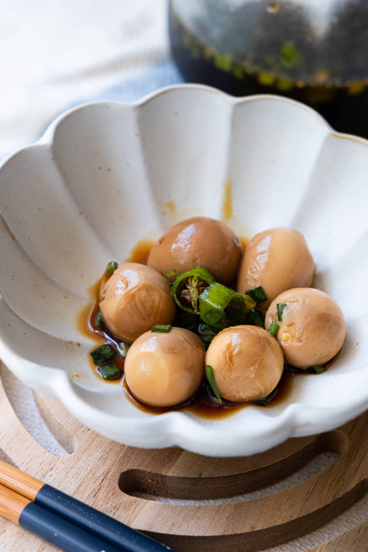 Flavorful soy sauce quail eggs in a small plate with chili pepper. 