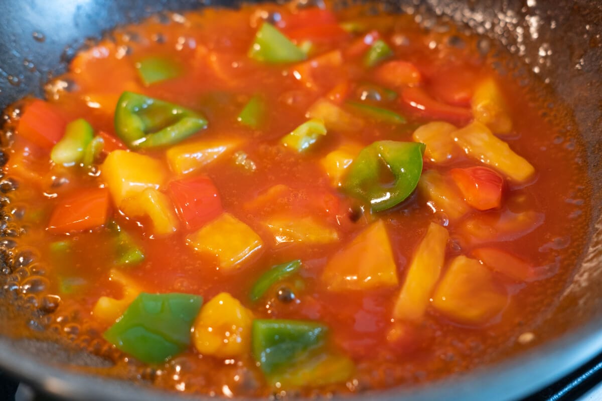 Cook sweet and sour sauce with bell peppers and pineapples. 